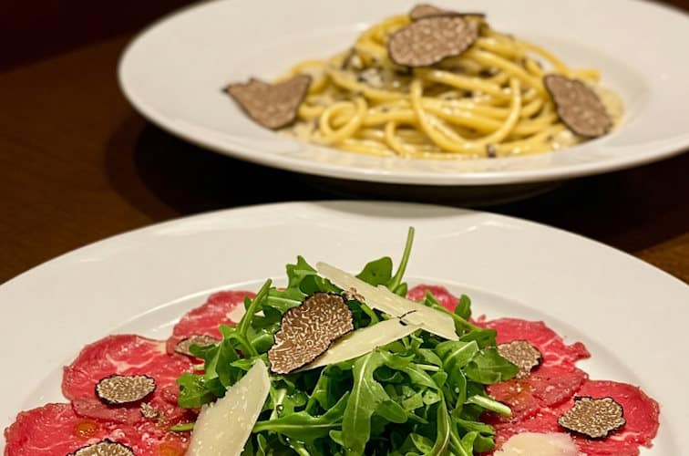 RIndscarpaccio mit Trüffelscheiben und Ruccola als Beilage zu Trüffelnudeln serviert